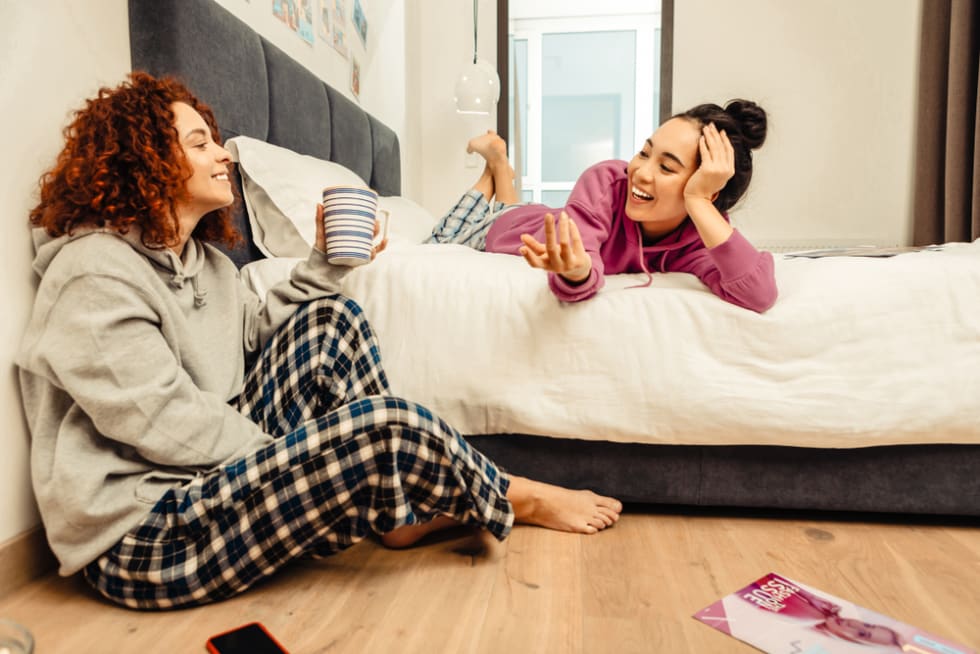 Enjoying day off. Two young beautiful roommates feeling cheerful while enjoying day off at home
