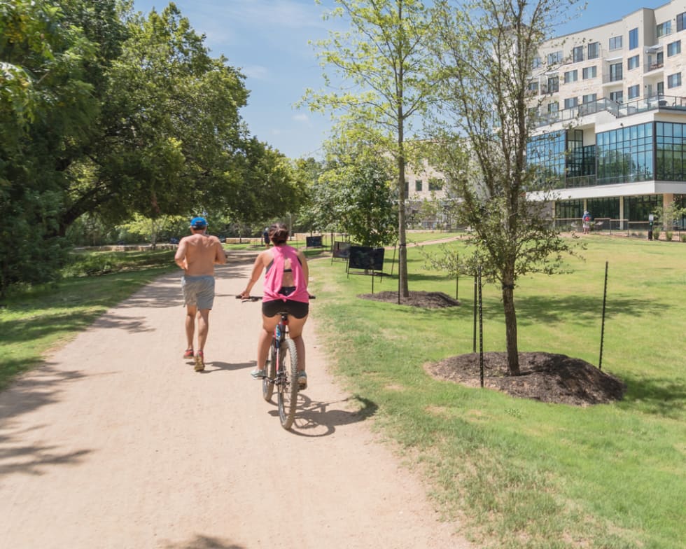 Sunny summer day in Austin, Texas with people enjoy running and biking on riverside natural soil trail, new apartment complex