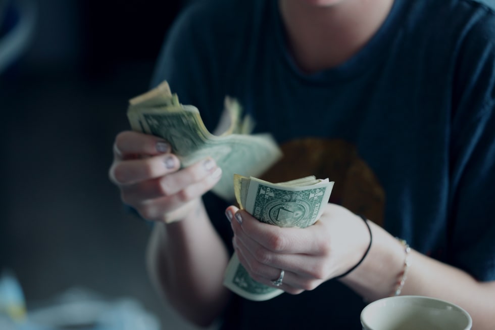 a person counting money to pay for an off-campus apartment