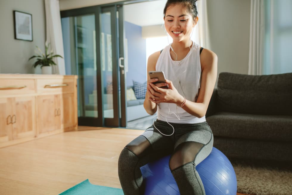 Woman listening to the music while sitting on a exercise ball at home.