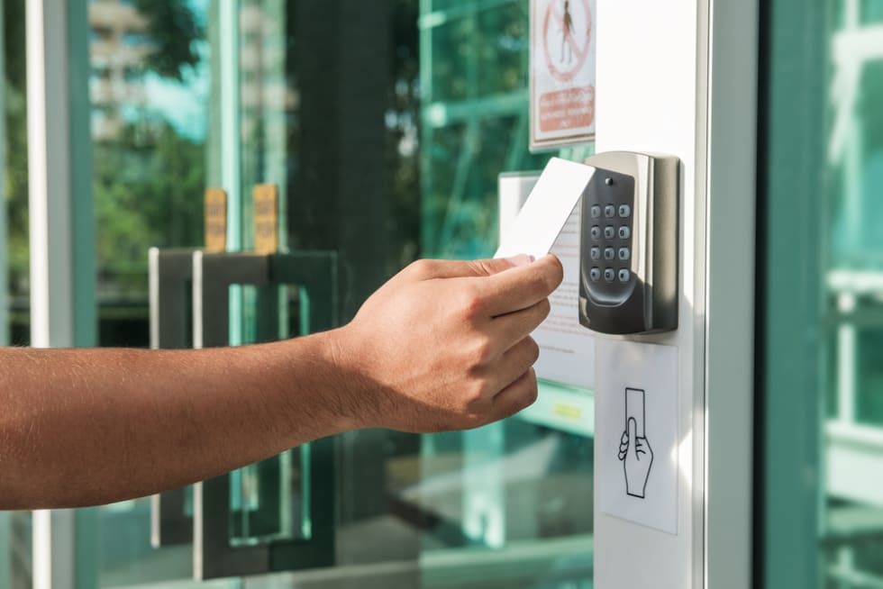 Hand using security key card scanning to open the door to entering private building. Home and building security system