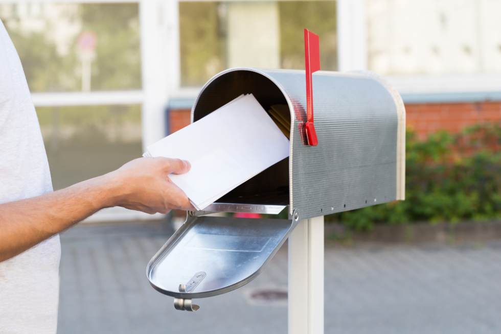  Close-up Of Person Putting Stack Of Letters In Mailbox