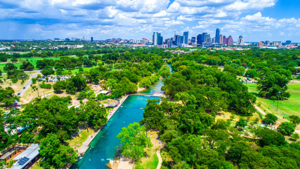 Aerial drone view above Barton Springs in Austin Texas with city skyline in background 
