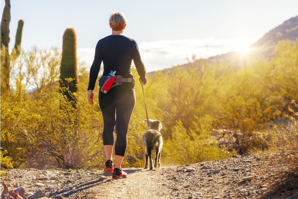 Unidentifiable woman walking a dog on a hiking path in Mountain View Park in Phoenix, Arizona