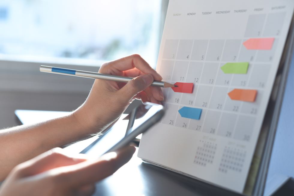 Event planner timetable agenda plan on schedule event. Business woman checking planner on mobile phone, taking note on calendar desk on office table. Calendar event plan, work planning