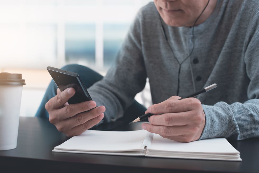 casual man listening to podcast app on mobile phone during working from home