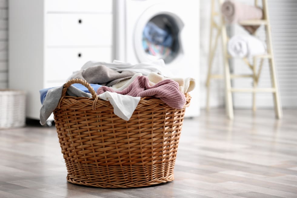 Wicker basket with dirty laundry on floor indoors, space for text