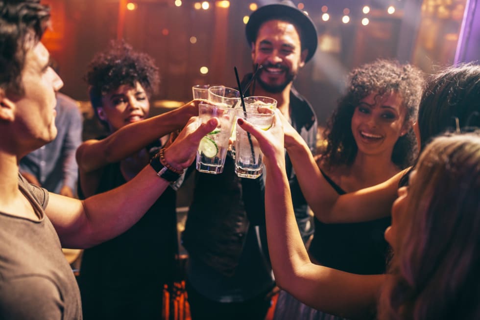 Group of friends having drinks at the night club party. Young people enjoying at a bar toasting cocktails