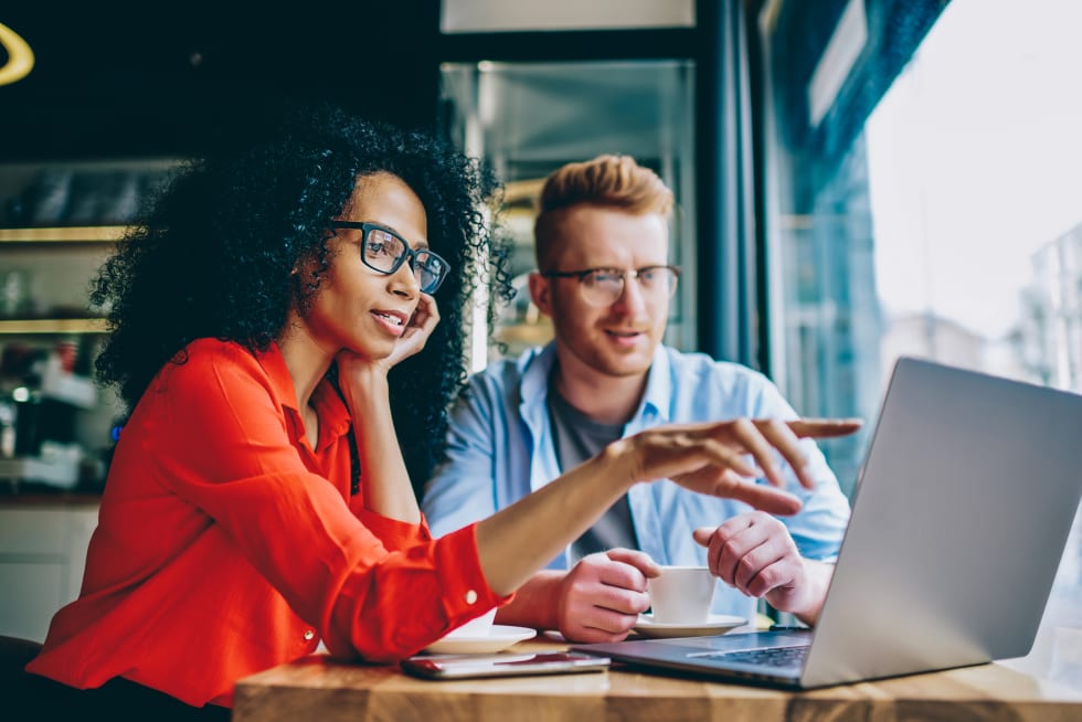 female graphic designer pointing with finger on laptop computer during collaboration 