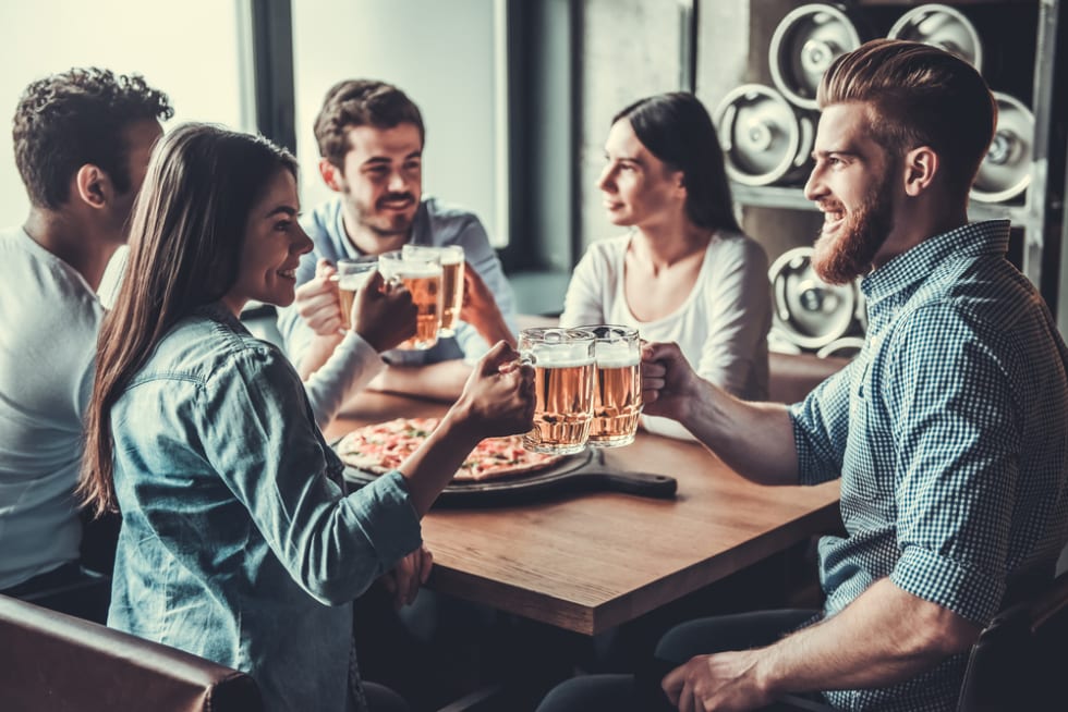 Meeting old friends at pub clinking drinks
