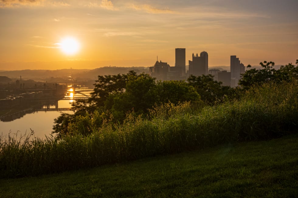 The sun rises over Pittsburgh, PA, USA at the confluence of the Allegheny, Monongahela and Ohio rivers, seen from a popular city park, Mount Washington.