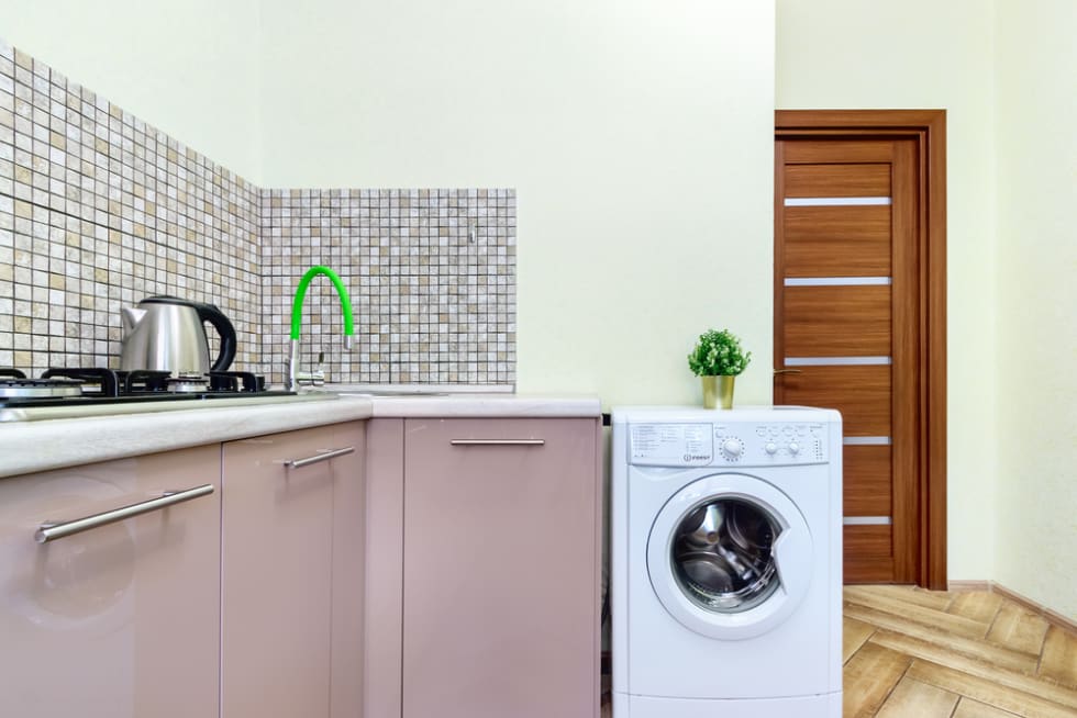 Interior of cheap simple kitchen with wooden counter and white washing machine