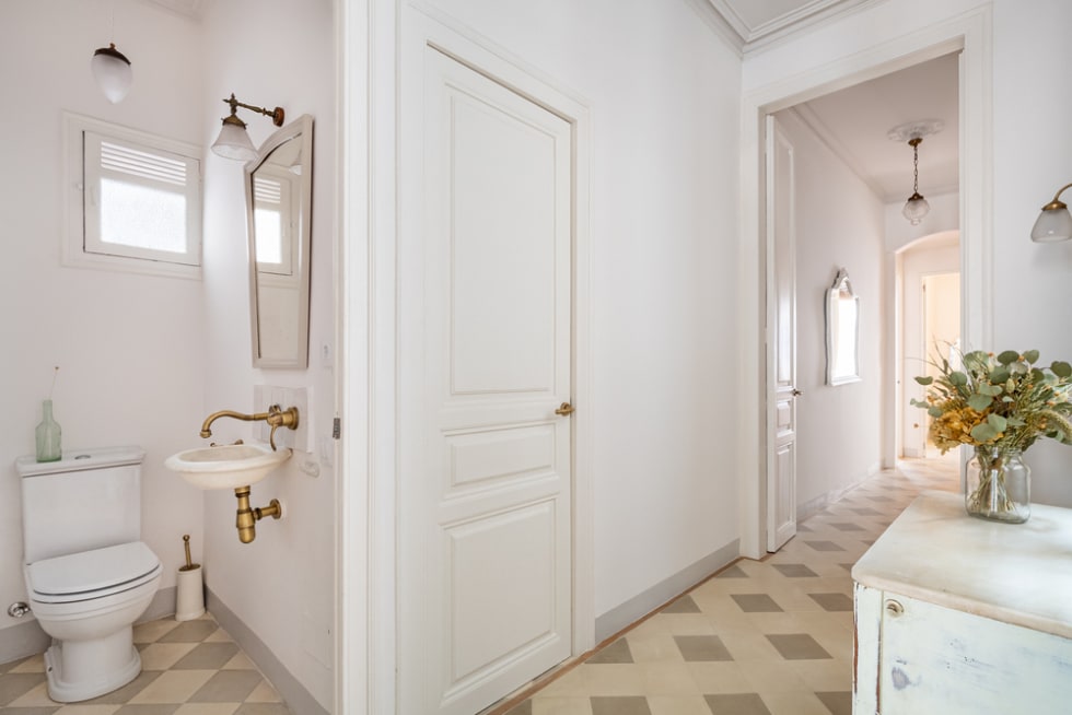 Hallway decorated in vintage style overlooking a long corridor and narrow toilet