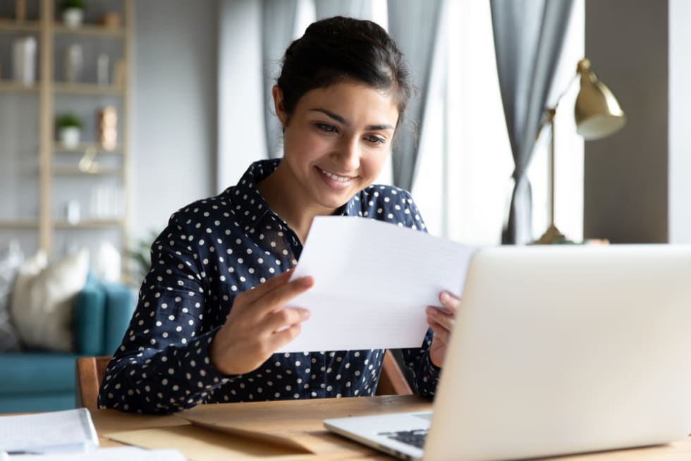 Woman smiling and looking at her paycheck - ApartmentList