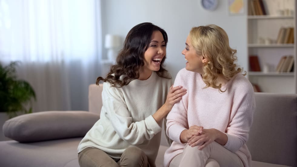 Cheerful female friends laughing at home, having fun together, relationship