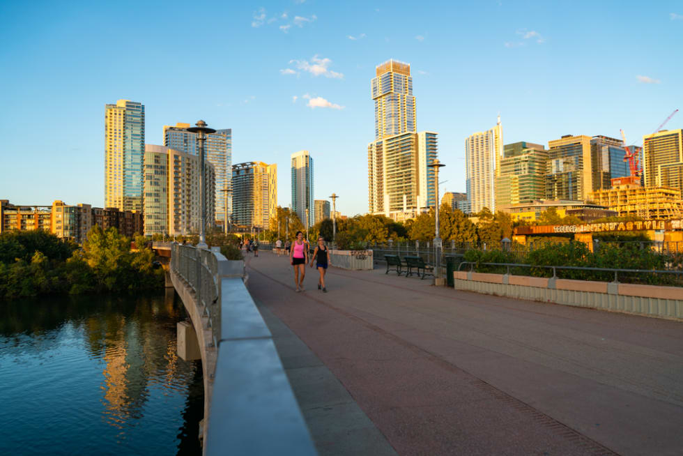 Enjoying the Town Lake Pedestrian Bridge with walkers and bike riders in Austin Texas Downtown Skyline Cityscape at Sunset