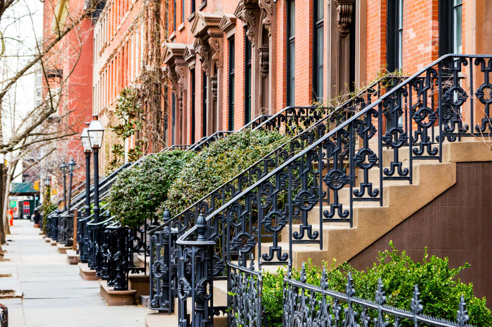 Row of old brownstone buildings along an empty sidewalk block in the West Village neighborhood of Manhattan, New York City NYC - best neighborhoods in New York