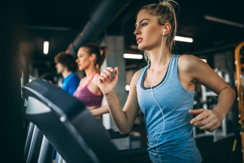Young people running on a treadmill in health club - rent an apartment remotely