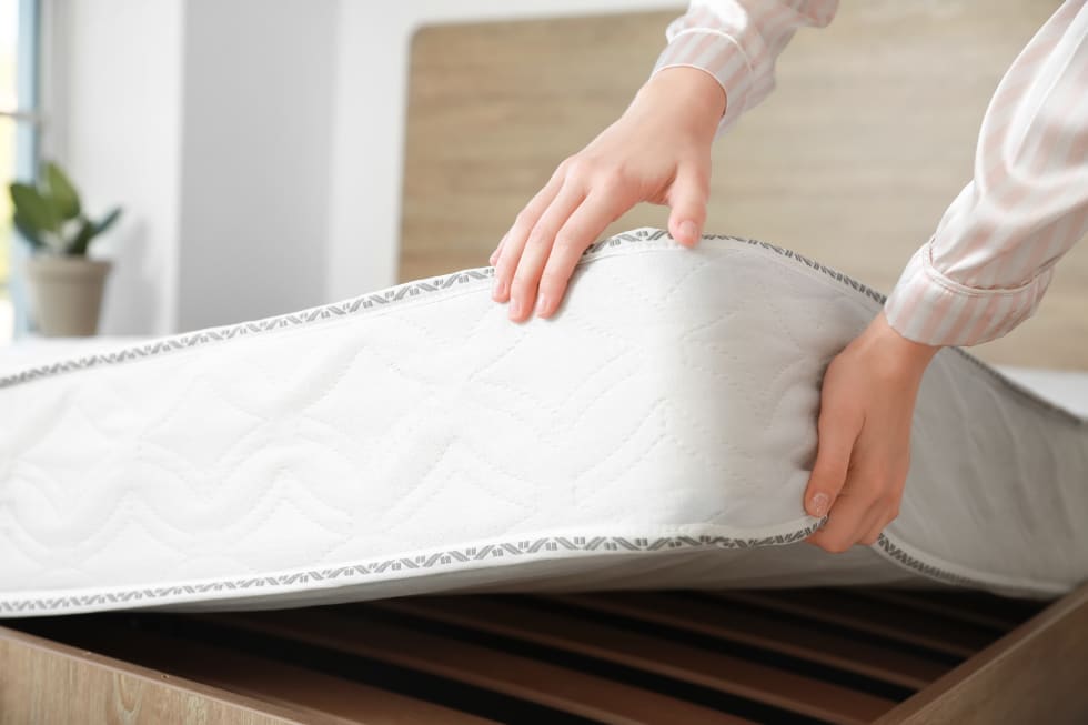 Woman putting soft orthopedic mattress on bed - soundproofing an apartment