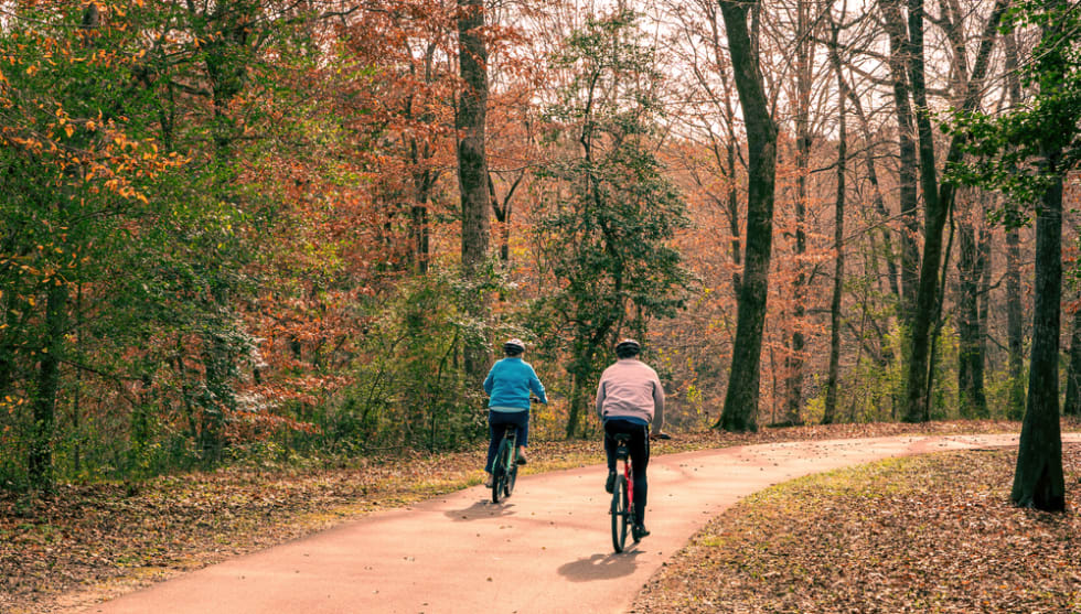 A Senior Couple Riding Bikes on the Neuse River Trail in Autumn in Raleigh, NC