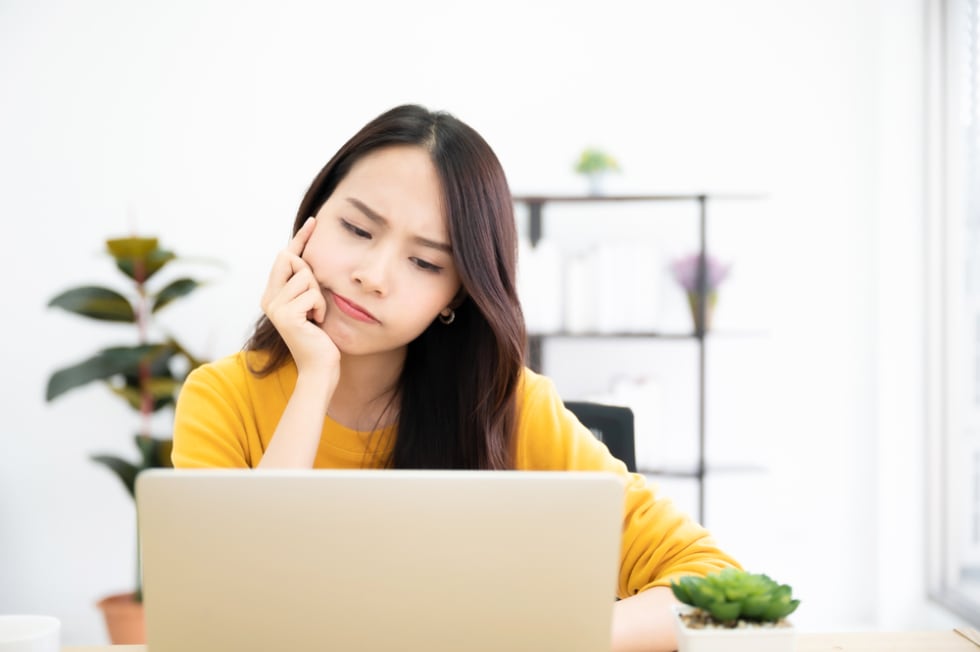 Asian young woman seriously working on computer laptop in house. 