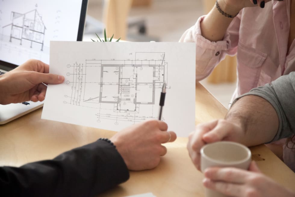 Architect or interior designer showing new apartment plan to couple at meeting, realtor consulting customers making real estate offer