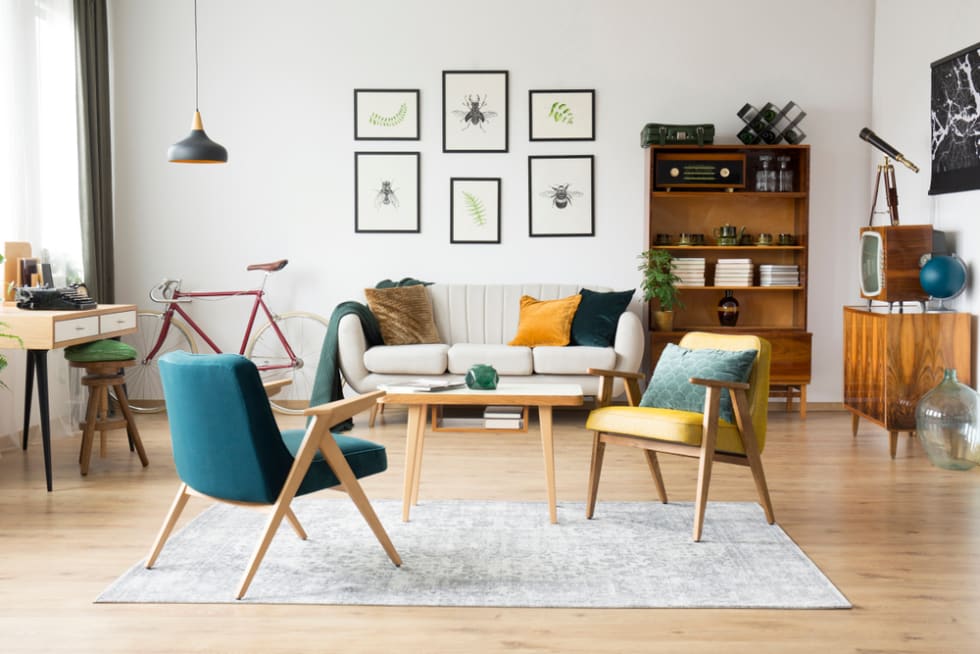 Stylish vintage furniture in a spacious flat interior with beige sofa, chairs and posters on the wall