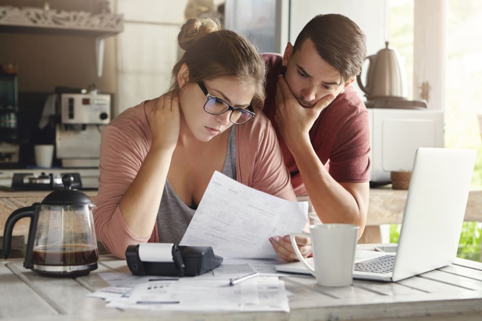 family having debt problems, not able to pay out their loan. Female in glasses and brunette man studying paper form bank while managing domestic budget together in kitchen interior