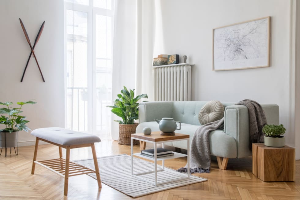 Stylish scandinavian living room with design mint sofa, furnitures, mock up poster map, plants and elegant personal accessories. Modern home decor. Bright and sunny room