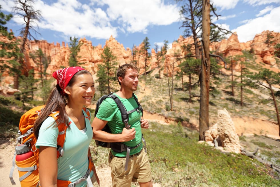 People hiking - couple hikers in Bryce Canyon walking smiling happy together. 
