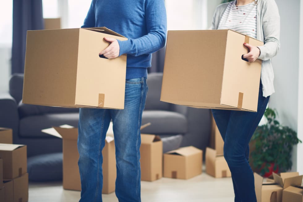  Couple moving into new apartment. Lot of packing boxes around them.