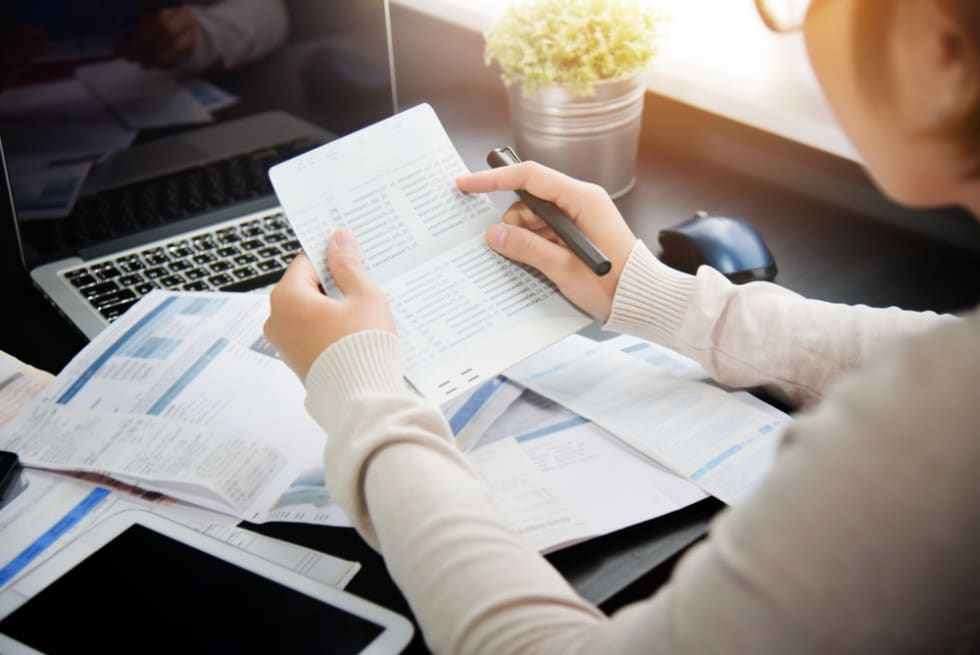 Woman at desk and computer looking at bills