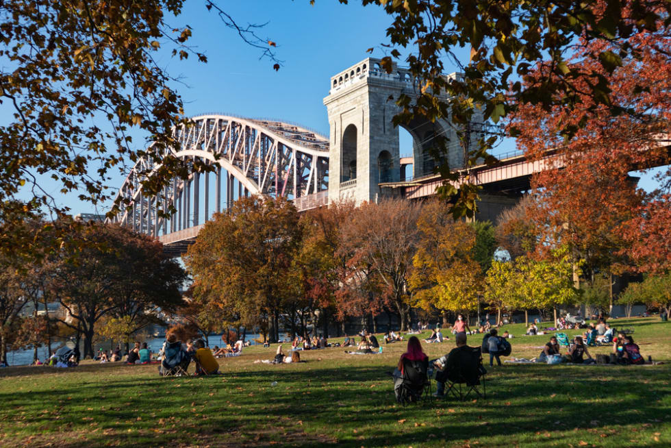 Astoria Park with the Hell Gate Bridge and a Field with People and Colorful Trees during Autumn