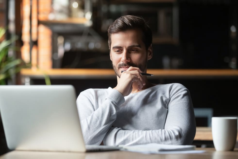 Thoughtful businessman think of online project looking at laptop at workplace, dreamy professional consider solution sit at work desk with computer, student search new idea inspiration in office cafe