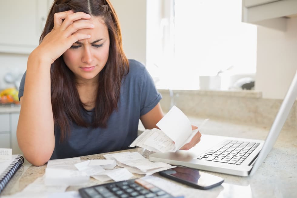 Woman looking worried over bills in kitchen - rental increase