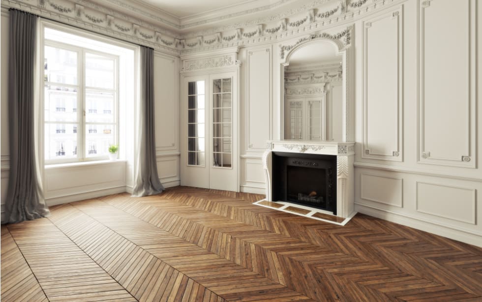 Empty room of an elegant residence with fireplace ,white trim Victorian accent interior space and herringbone wood flooring. 