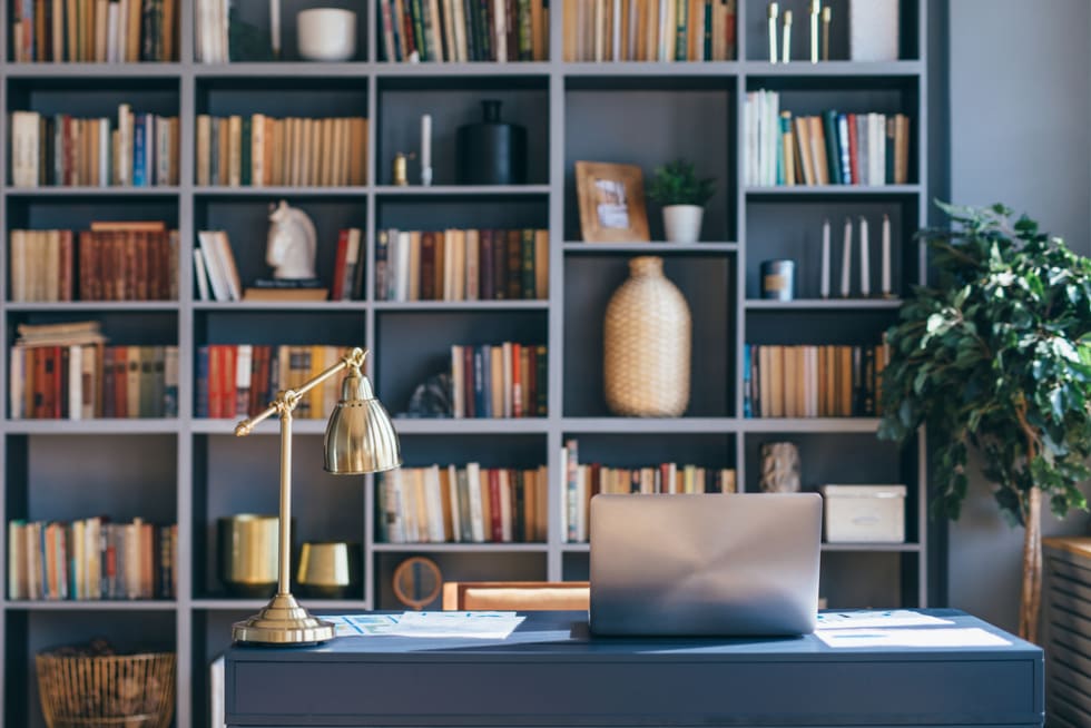 Table with laptop in home office interior with a bookshelf