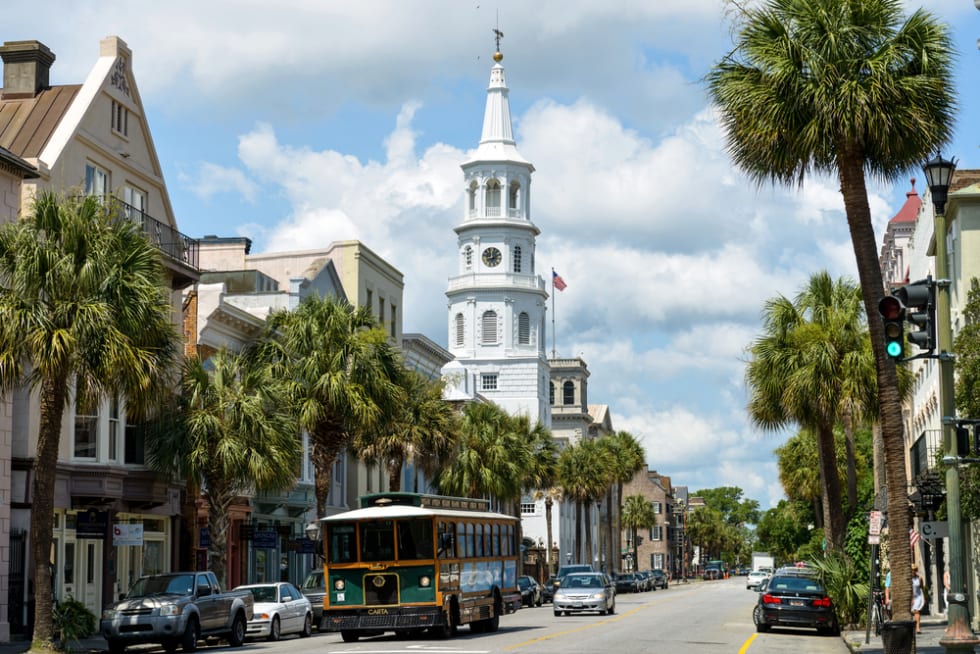 A Charleston DASH trolley, part of the CARTA Transit System, driving on the historic Broad street in front of St Michaels Church in Downtown Charleston