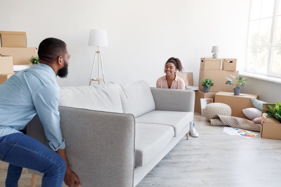 family carry sofa to new apartment with cardboard boxes. Teamwork, rearrangement of furniture, apartment renovation, new design and relocation at home, free space