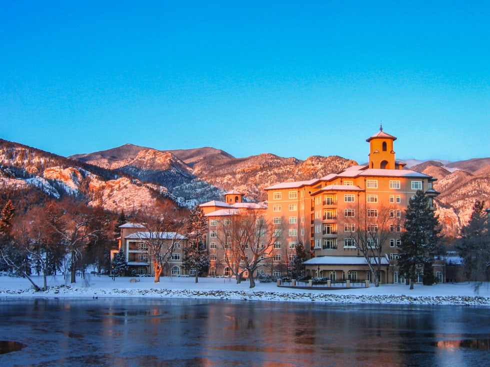 The Broadmoor Resort West Tower across Cheyenne Lake on a frosty late winter morning at dawn with Rocky Mountains front range under a brilliant sky.