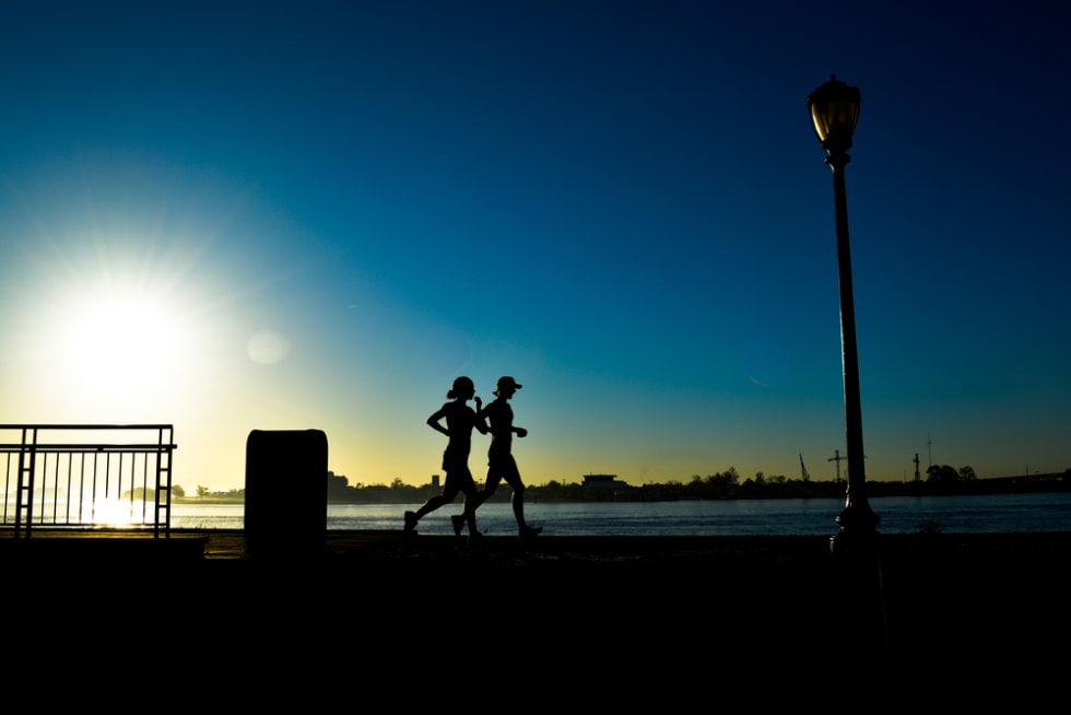 Early Morning Joggers Silhouette Against Blue Morning Sky Along Mississippi in New Orleans