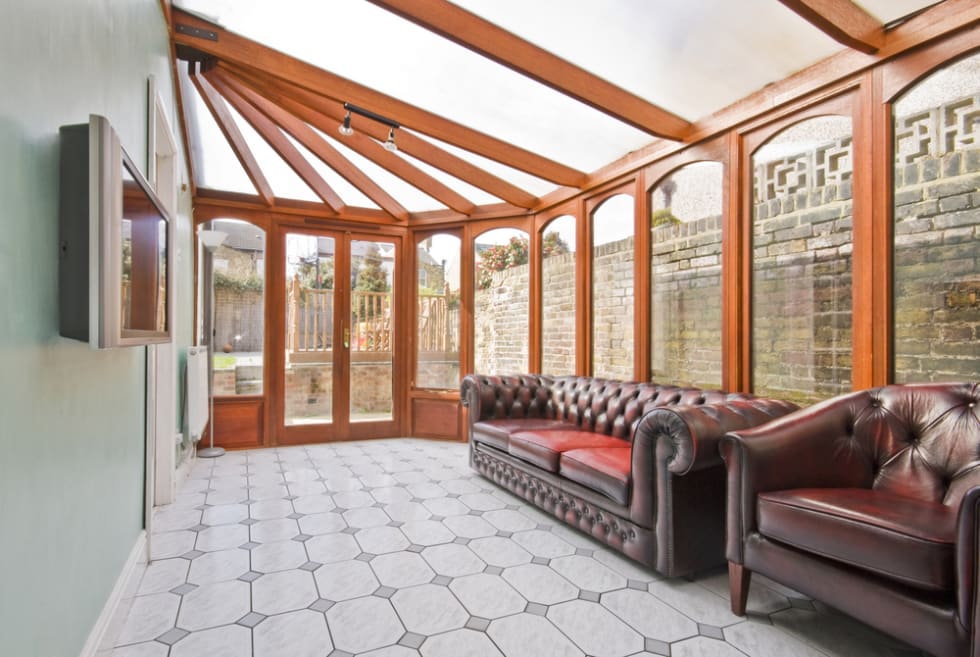 conservatory extension of a family home with leather sofa and tiled floor