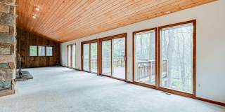 Welcome home! One of a kind, strikingly designed 2-level hillside chalet built on 1 1/2 acres of wooded property with stream surrounded by park land. Gallery 10