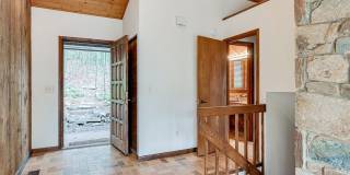 Welcome home! One of a kind, strikingly designed 2-level hillside chalet built on 1 1/2 acres of wooded property with stream surrounded by park land. Gallery 3