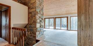 Welcome home! One of a kind, strikingly designed 2-level hillside chalet built on 1 1/2 acres of wooded property with stream surrounded by park land. Gallery 4