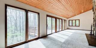 Welcome home! One of a kind, strikingly designed 2-level hillside chalet built on 1 1/2 acres of wooded property with stream surrounded by park land. Gallery 9