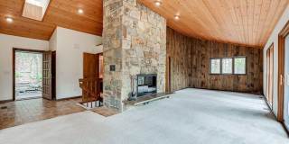 Welcome home! One of a kind, strikingly designed 2-level hillside chalet built on 1 1/2 acres of wooded property with stream surrounded by park land. Gallery 6